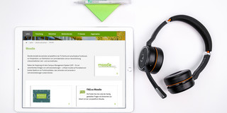 Ein weißes Tablet, daneben liegt ein Headset