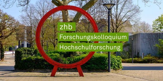 Foto des roten Zahnrads auf dem Martin-Schmeißer-Platz an der TU Dortmund. Aus dem Zahnrad ragt von links nach rechts der Schriftzug zhb Forschungskolloquium Hochschulforschung heraus