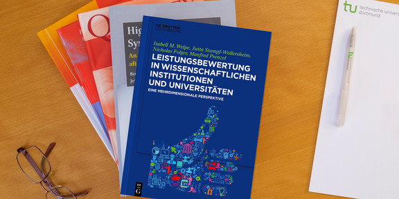 Bücherstapel, daneben eine Brille und ein Notizblock
