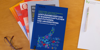 Bücherstapel, daneben eine Brille und ein Notizblock