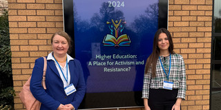 Foto: Prof. Liudvika Leišytė und Nina Bieling stehen vor einem Banner der SRHE Konferenz 2024