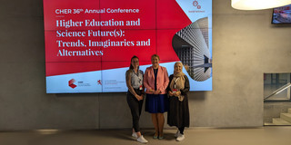 Gruppenfoto von Anja Westphal, Prof. Liudvika Leišytė und Sude Pekşen vor einem Banner der CHER Jahreskonferenz 2024