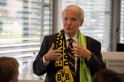 Foto: Prof. Shaker A. Zahra spricht vor einem Publikum. Er trägt einen BVB- und TU Dortmund-Schal.
