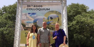 Photo of Anna-Lena Rose, Prof. Jay R. Dee and Prof. Liudvika Leišytė in front of a banner of the EGOS Colloquium 2023
