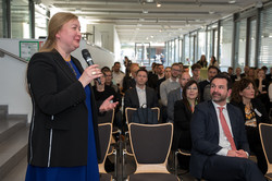 Foto: Liudvika Leišyte steht mit einem Mikrofon vor dem sitzenden Publikum