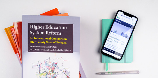 A stack of books, next to it a smartphone