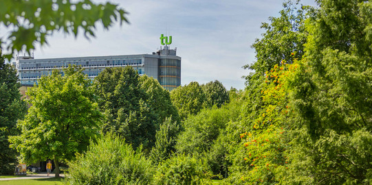 Das Mathematikgebäude mit grünen Bäumen im Vordergrund.