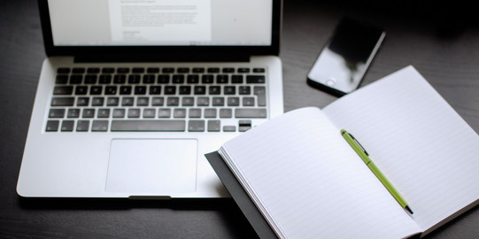 Seminar Papers: Word Template Laptop, smartphone and notebook with pen lying on a table.