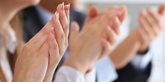 Several hands of women and men clap.